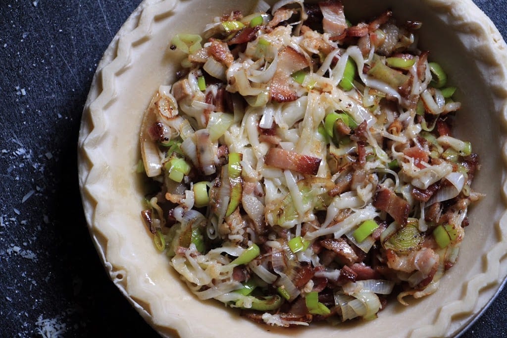 Fill the pie shell with the mixed leeks, bacon, and cheeses