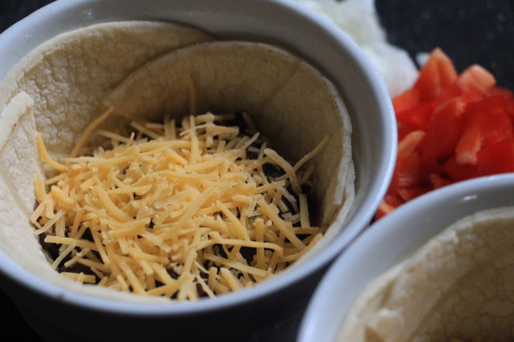 Fold the tortillas to form a bowl and add the beans and cheese