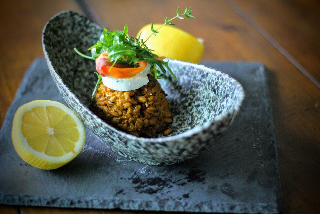 Scoop risotto into warm bowls, then top with goat cheese and a garnish of small salad greens, shaved carrots, lemon zest, and truffle oil.