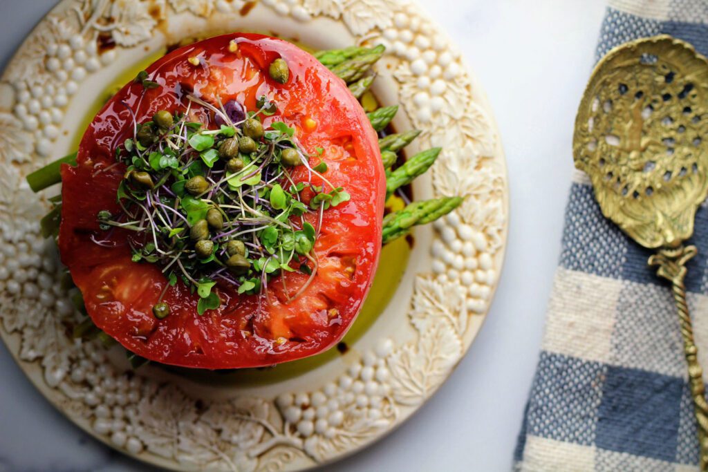 Stacked caprese garnished with microgreens and capers