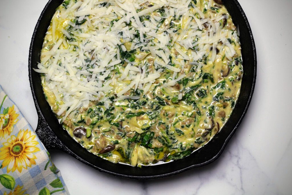Pour the frittata into a greased baking dish, top with cheese, and bake.