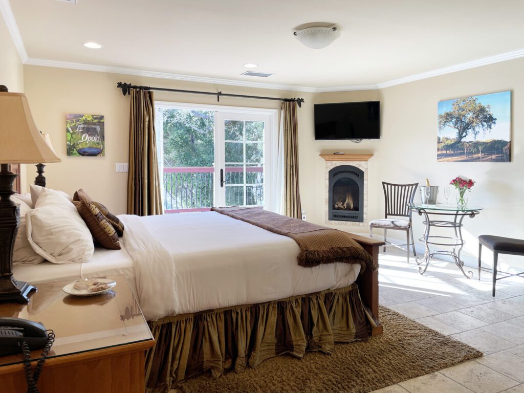 King bed, French doors, fireplace, and bistro table inside the Rhapsody Suite