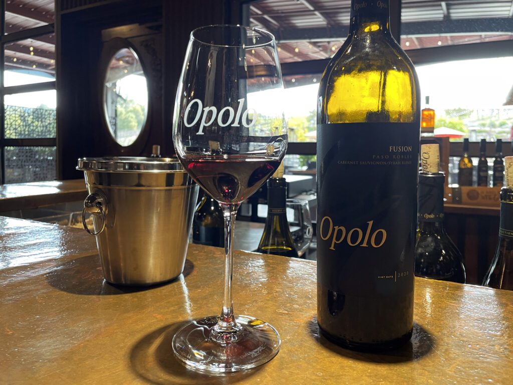 A tasting glass of red wine with a bottle of Opolo's Fusion
