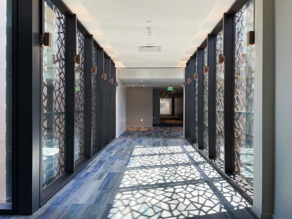 Sunlight filters through a window screen with a Chinese inpsired cracked ice motif in the hallway of a hotel.