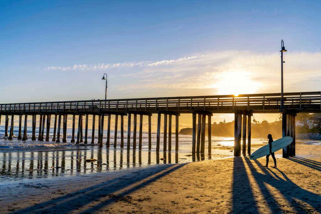 A surfer at sunset near the Cayucos Pier