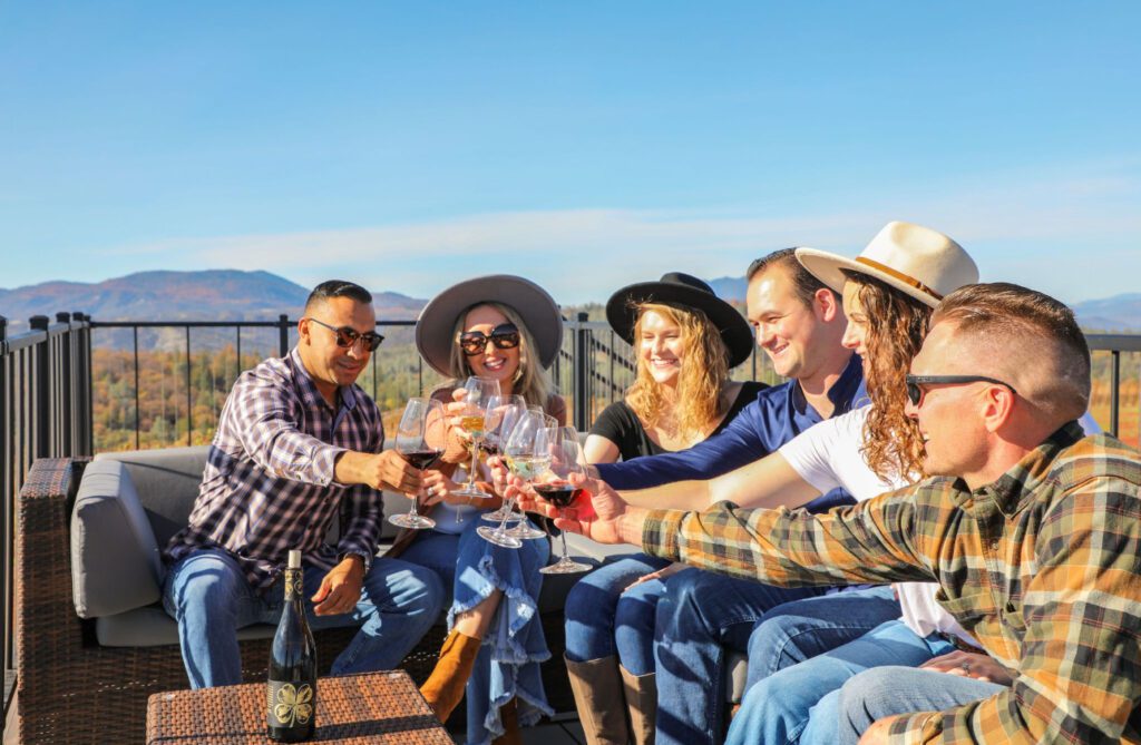 Group of people toasting with wine on a deck overlooking a vineyard