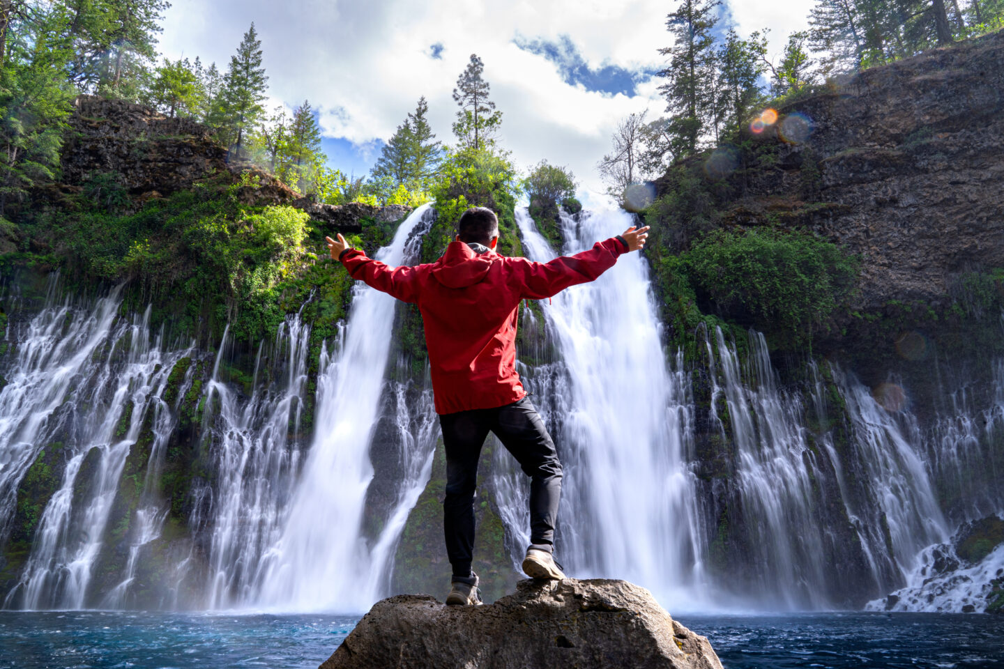 Man standing in front of a large waterfall