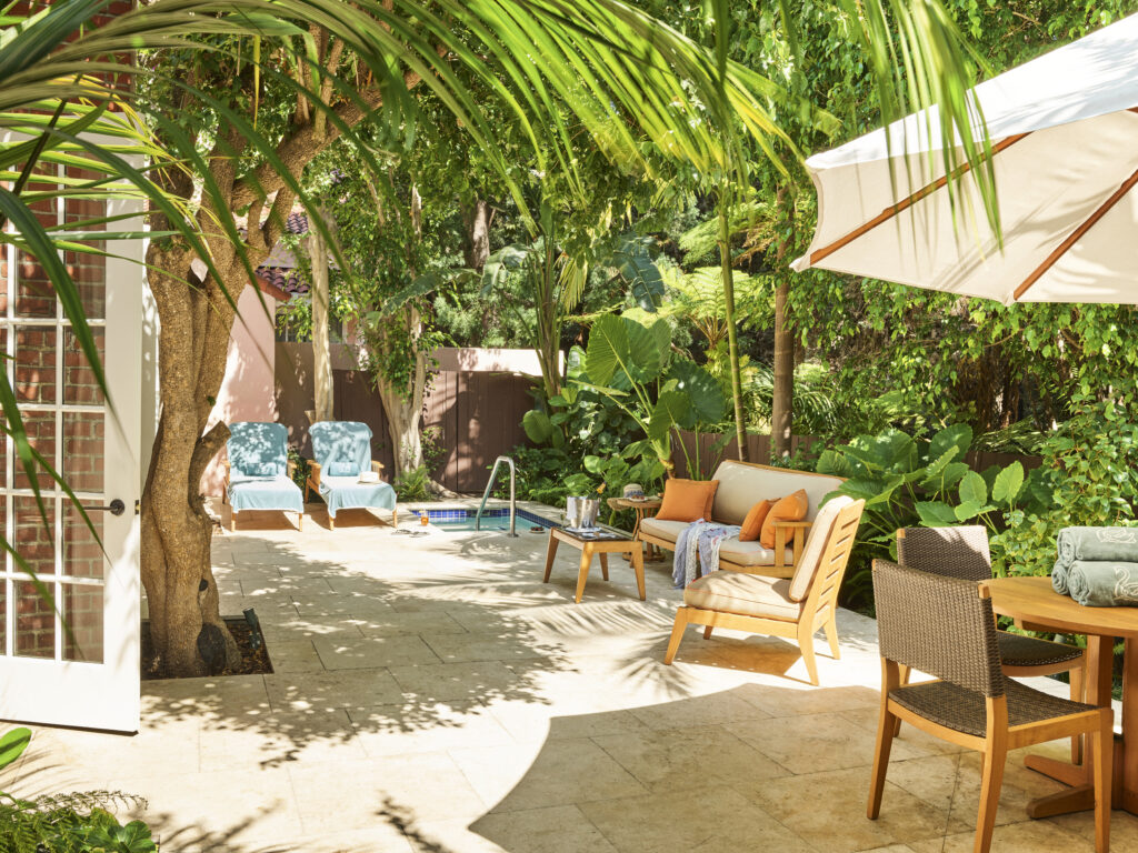 private outdoor courtyard with a hot tub, lounge seating, and tropical foliage