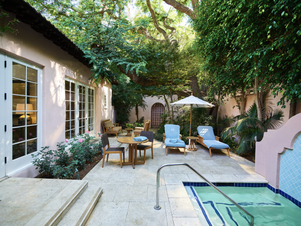 private outdoor courtyard with a hot tub, lounge seating, and tropical foliage