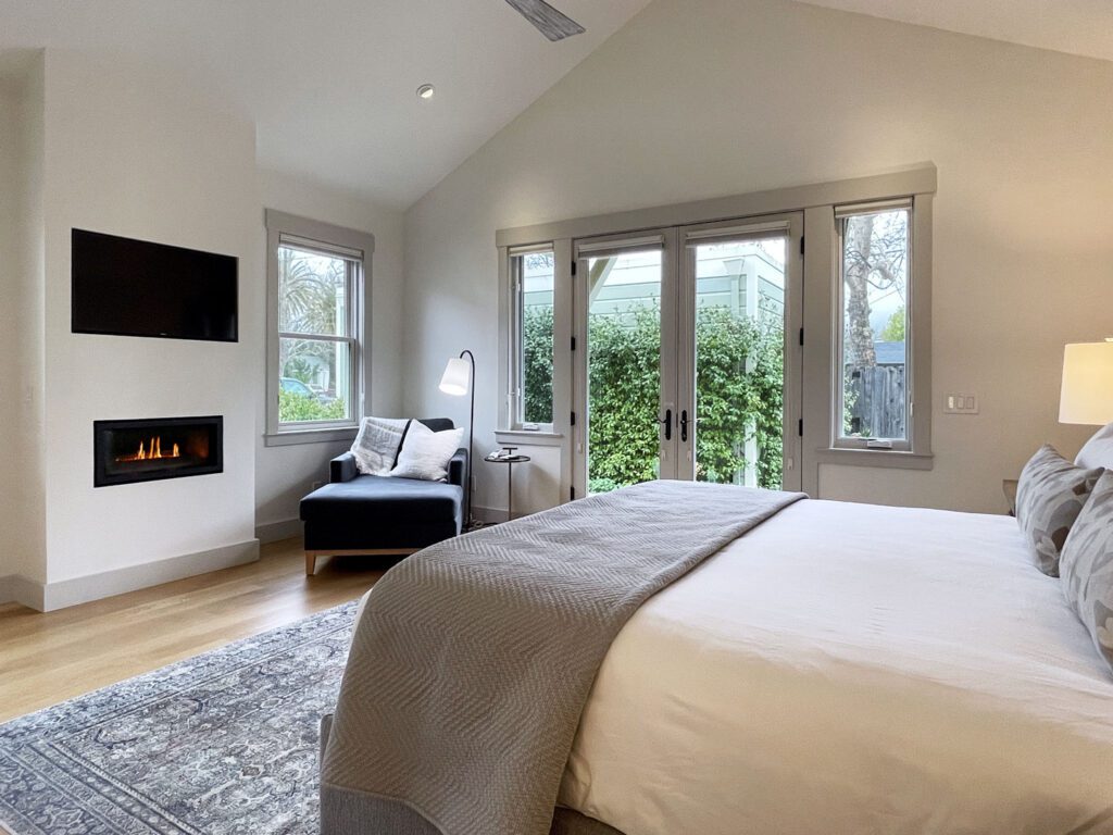 A cottage bedroom with a fireplace and French doors opening to a private patio